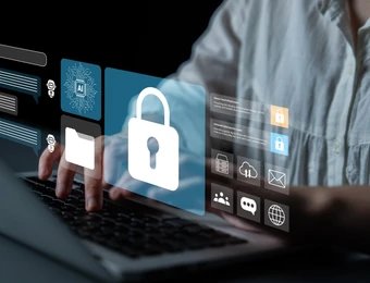 Person tippt auf Laptop; zentrale blaue Schloss-Icon mit digitalen Widgets und weiteren Symbolen, dunkler Hintergrund.