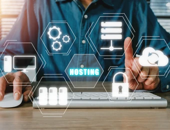 Person bedient Tastatur und Maus; holografische sechseckige Symbole zeigen Server, Zahnräder, Cloud und Hosting.