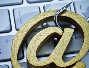Großes goldenes '@'-Symbol auf einer hellgrauen Computertastatur.