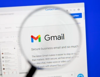 Nahaufnahme eines Computerbildschirms: Gmail-Logo wird durch eine Lupe vergrößert angezeigt.