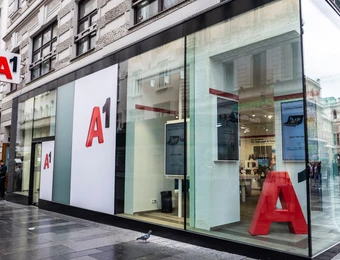 Moderne Ladenfront mit Glasfassade, große rote A1-Schriftzüge an weißen Paneele; Straßenszene sichtbar.