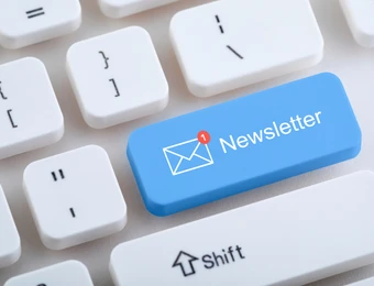 Blaue Tastenkappe mit Newsletter und Briefumschlags-Symbol auf weißer Tastatur.