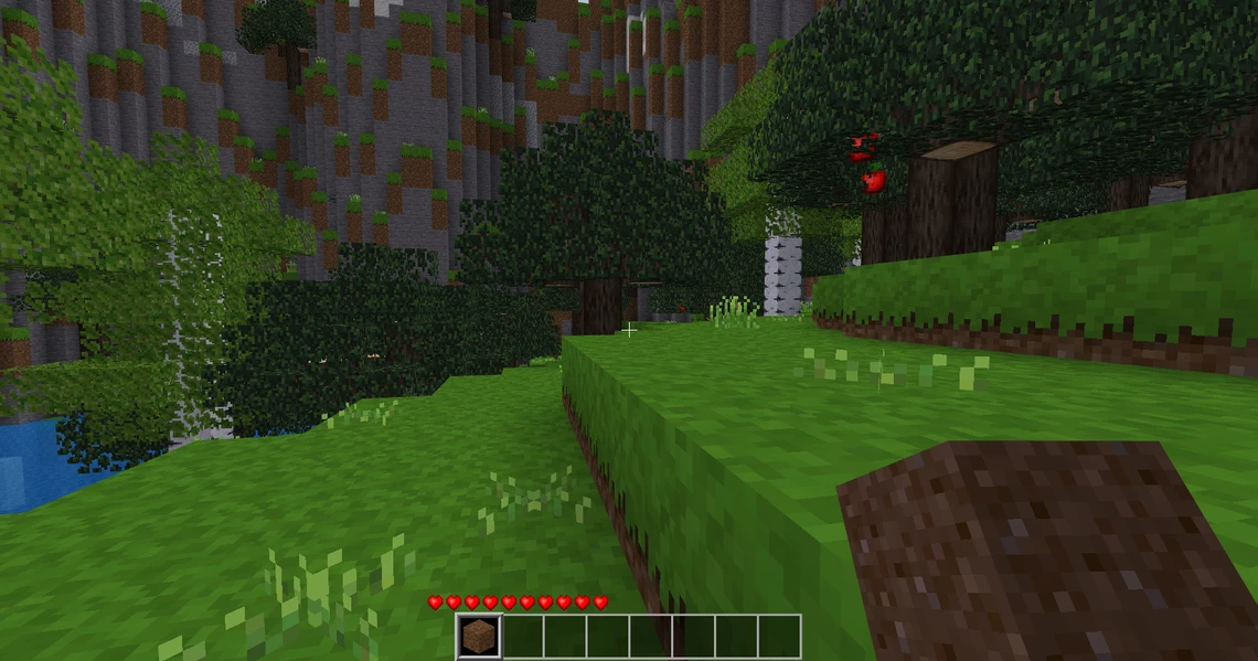 Minecraft-Szene: grüne Hügel, Bäume, Felsenwand links, Wasser unten links, Hand hält Dirt-Block im Vordergrund.