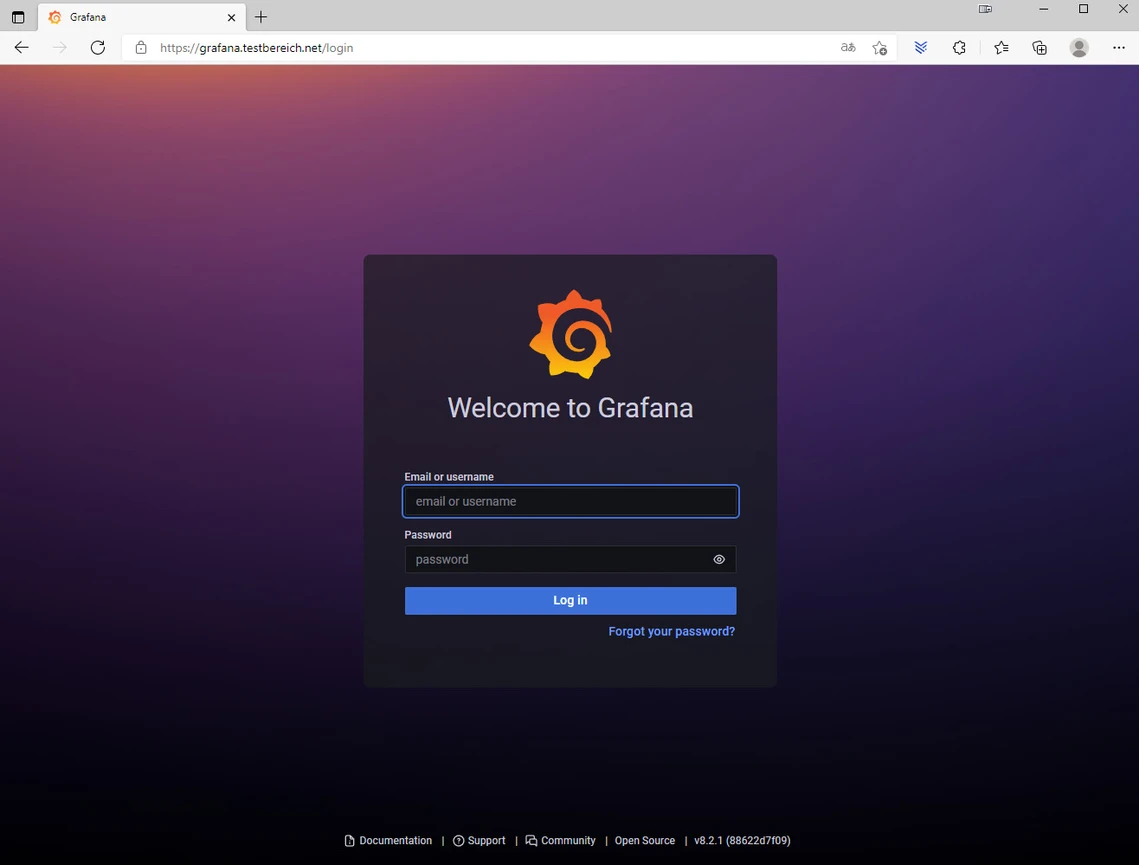 Bildschirm mit dunklem Grafana-Loginfenster, orangefarbenem Logo, Felder Email/Username und Password, blauem Log in-Button.