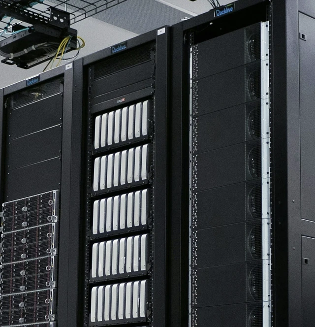 Mehrere Serverracks in einem Rechenzentrum, mit schwarzen Frontplatten, Laufwerken und sichtbaren Kabeln.