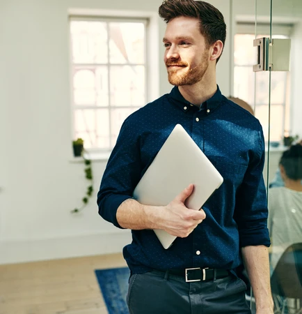 Ein Mann mit einem Laptop in der Hand geht durch ein Büro