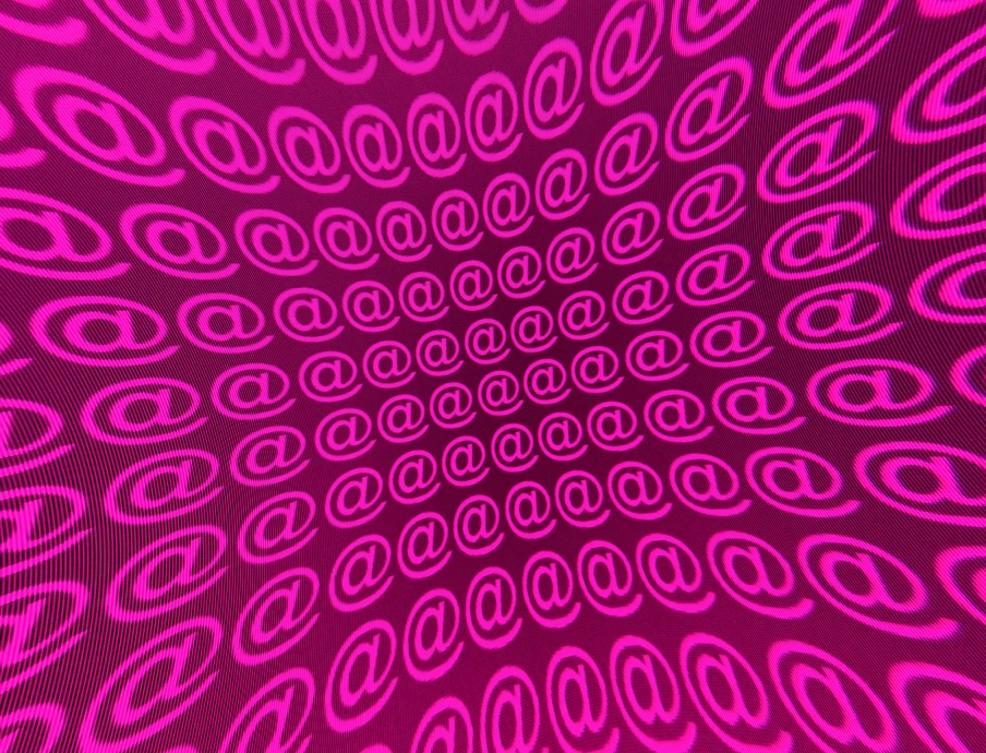 Leuchtend pinke @-Symbole in spiralförmigem Muster auf pinkem Hintergrund.