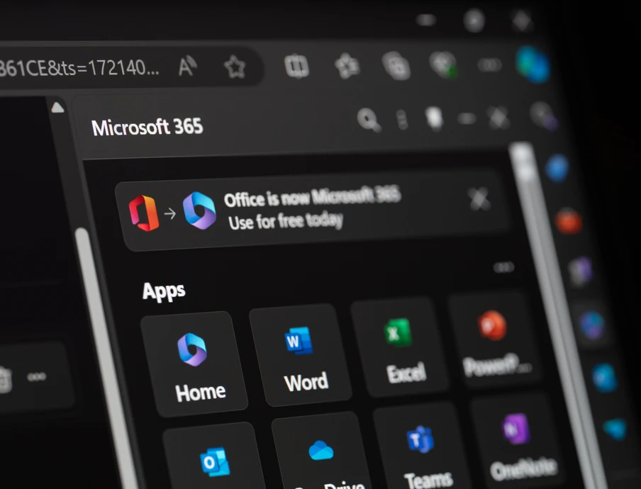 Bildschirm zeigt Microsoft 365-Apps im dunklen Layout; Kacheln für Word, Excel, PowerPoint, Teams, Outlook.