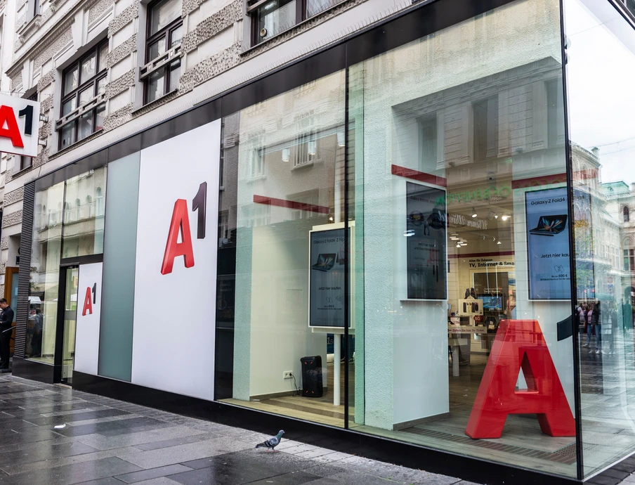 Moderne Ladenfront mit Glasfassade, große rote A1-Schriftzüge an weißen Paneele; Straßenszene sichtbar.