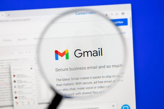 Nahaufnahme eines Computerbildschirms: Gmail-Logo wird durch eine Lupe vergrößert angezeigt.