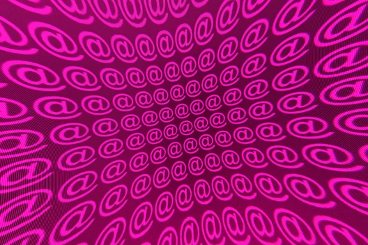 Leuchtend pinke @-Symbole in spiralförmigem Muster auf pinkem Hintergrund.