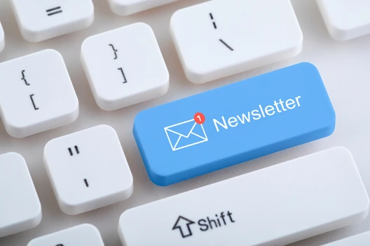 Blaue Tastenkappe mit Newsletter und Briefumschlags-Symbol auf weißer Tastatur.