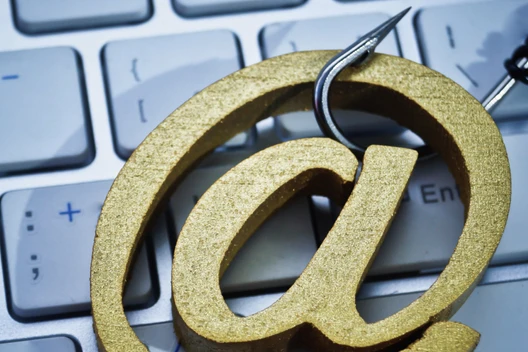 Großes goldenes '@'-Symbol auf einer hellgrauen Computertastatur.